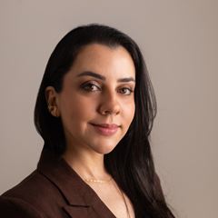Dra. Jéssica Hattge, de cabelos longos e escuros e blazer marrom, sorrindo levemente